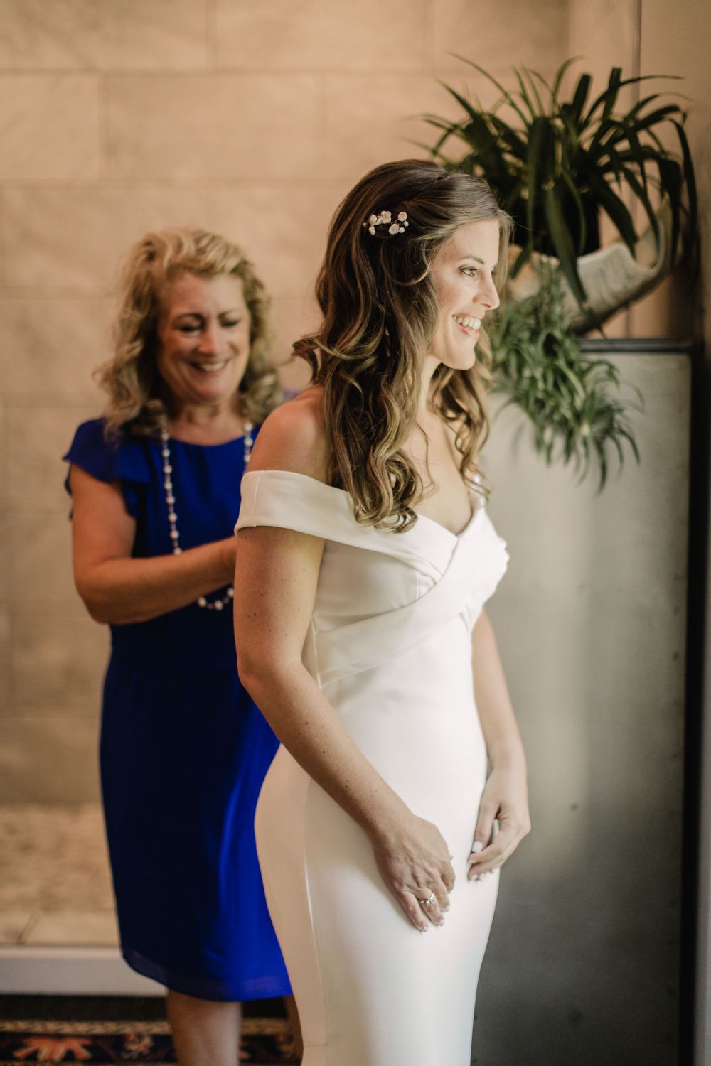 An elegant white off-shoulder wedding dress being prepared in an indoor setting.