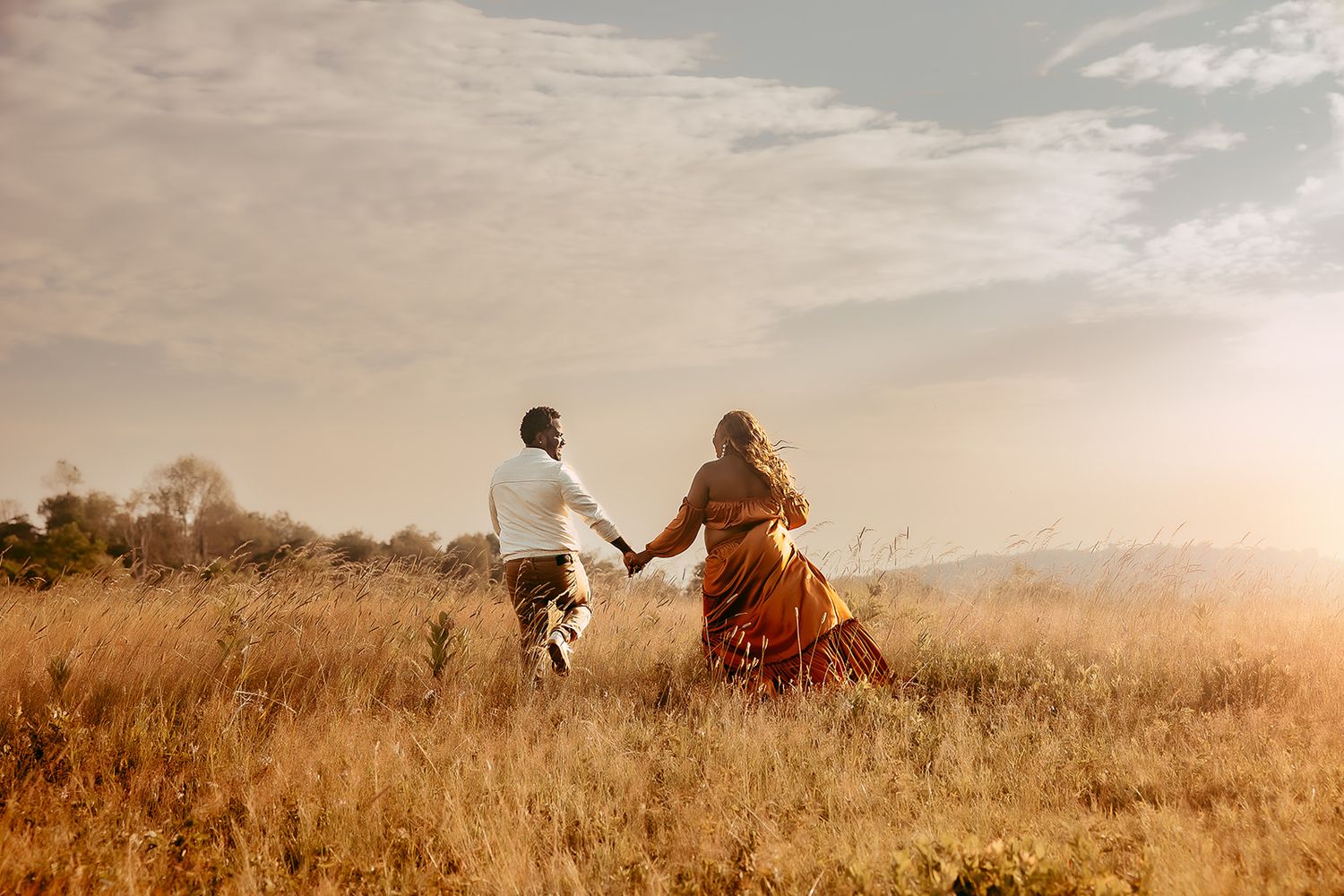A husband and wife walk hand in hand through Big Meadows during their maternity photoshoot.
