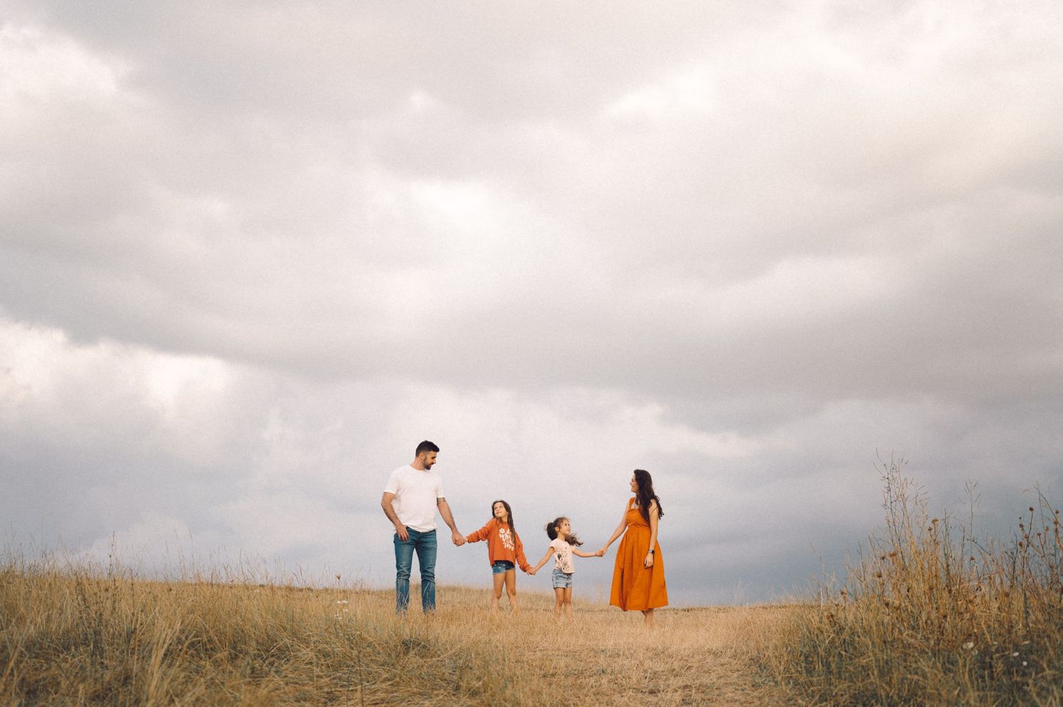People walking together on a hilltop path against cloudy sky.