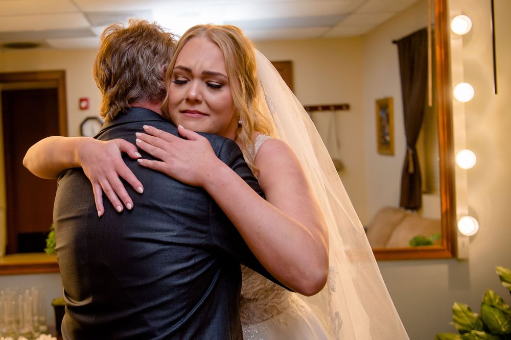 Emotional embrace captured during wedding celebration indoors.