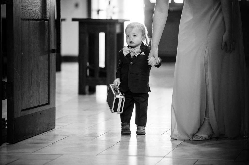 Small child in formal wear walking excitedly down hallway in black and white photo.