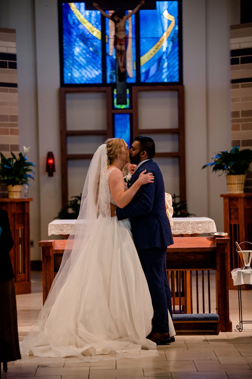 A romantic moment shared during a wedding ceremony in front of a dramatic stained glass window.
