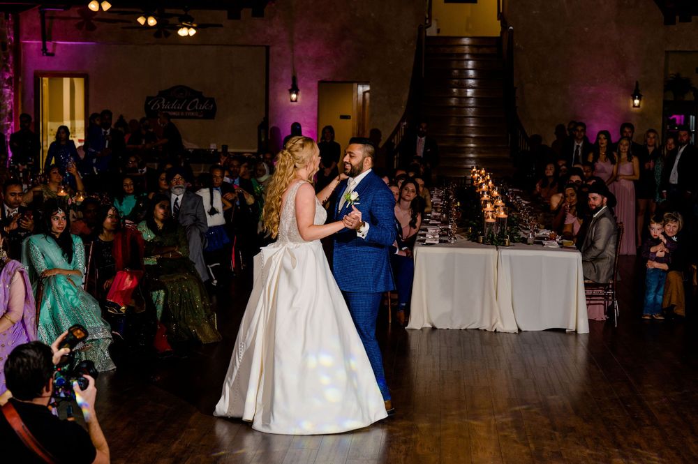 A couple shares their first dance at their wedding reception in a dimly lit ballroom.