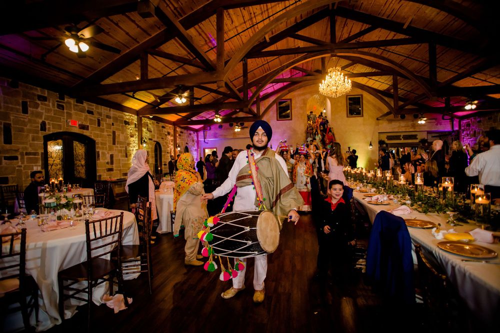Festive wedding reception in a stone-walled venue with elegant table settings and colored lighting.