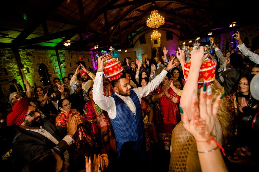 Energetic wedding party dance floor scene with colorful lighting and raised hands celebrating.