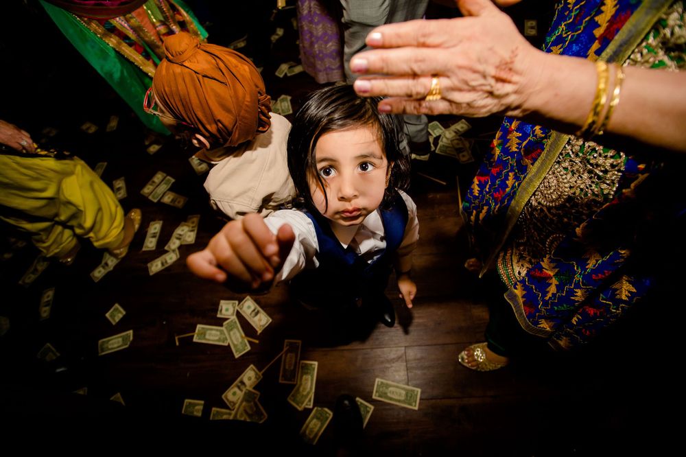 Young attendee on crowded dance floor reaching up during wedding celebration.