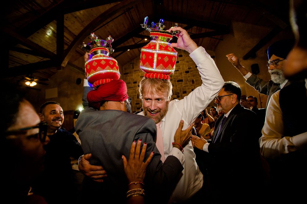 Wedding celebration with guests lifting decorative red crowns in a crowded venue.