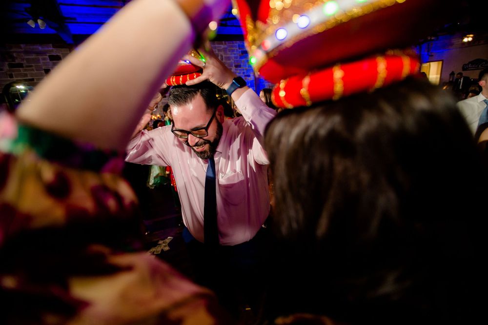 Guest dancing under colorful party lights at wedding reception.