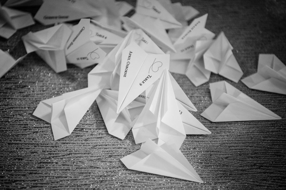 Collection of folded paper airplanes scattered on dark textured surface.