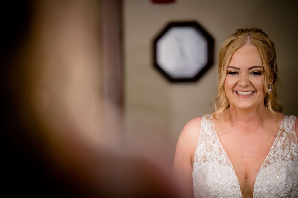 Person wearing white wedding dress smiling in indoor setting.