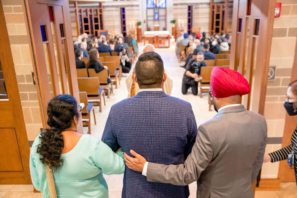 Three people standing together in formal attire at church ceremony.