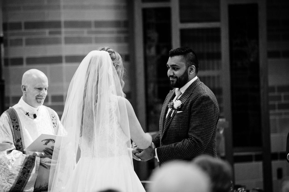 Black and white wedding ceremony photo in traditional church setting.