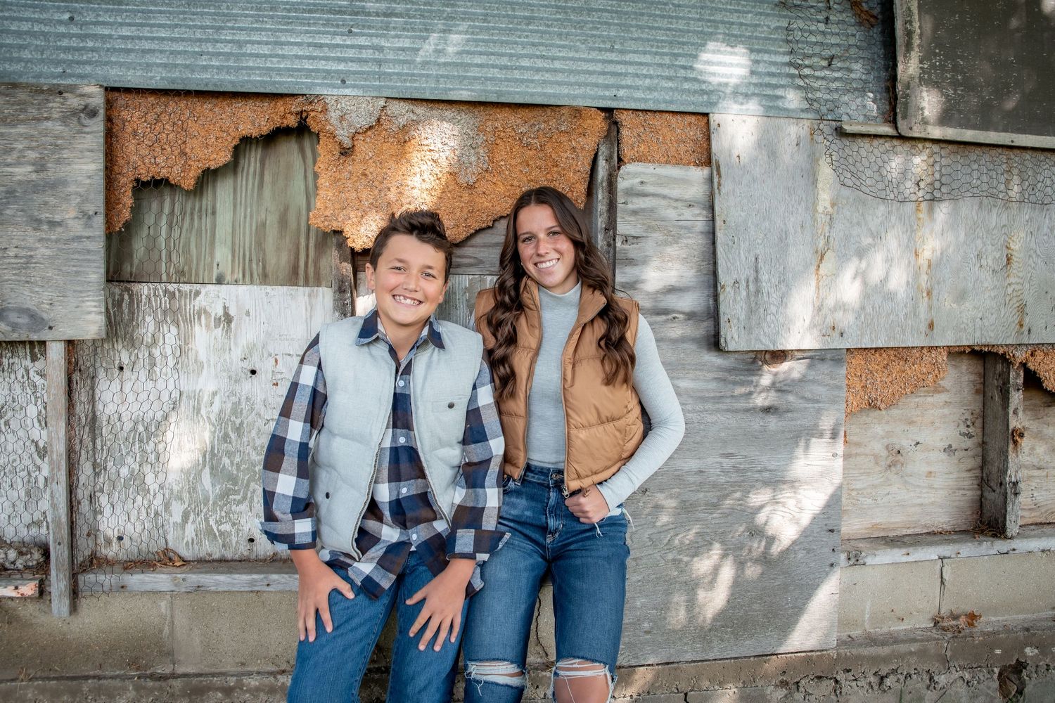 Family portraits taken against rustic brick wall with natural window lighting.