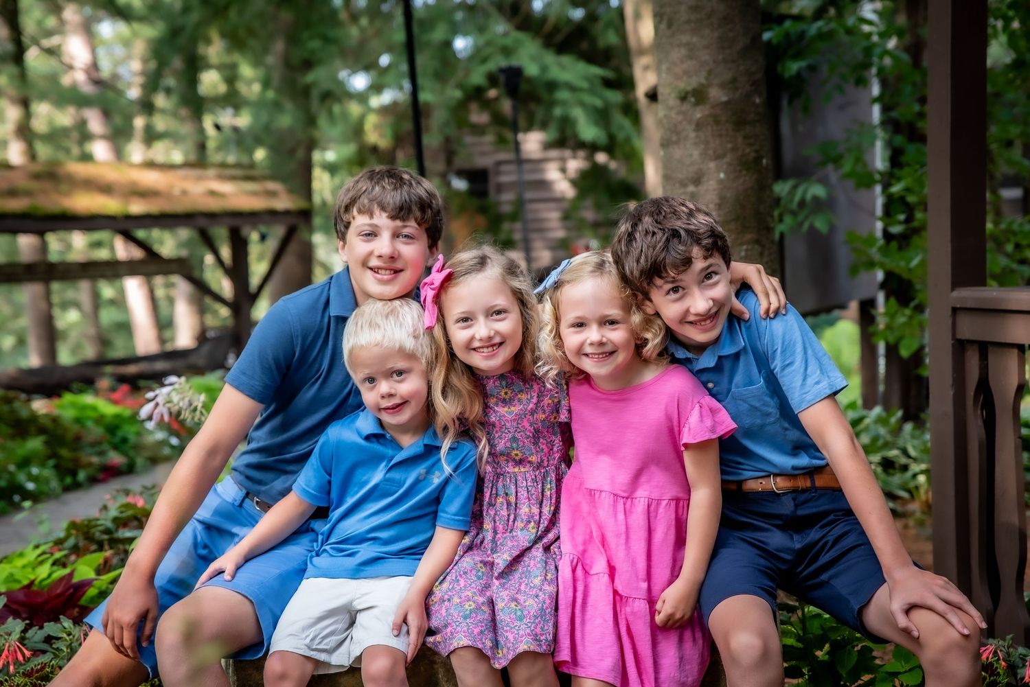 Group sitting together on wooden deck surrounded by lush summer greenery.
