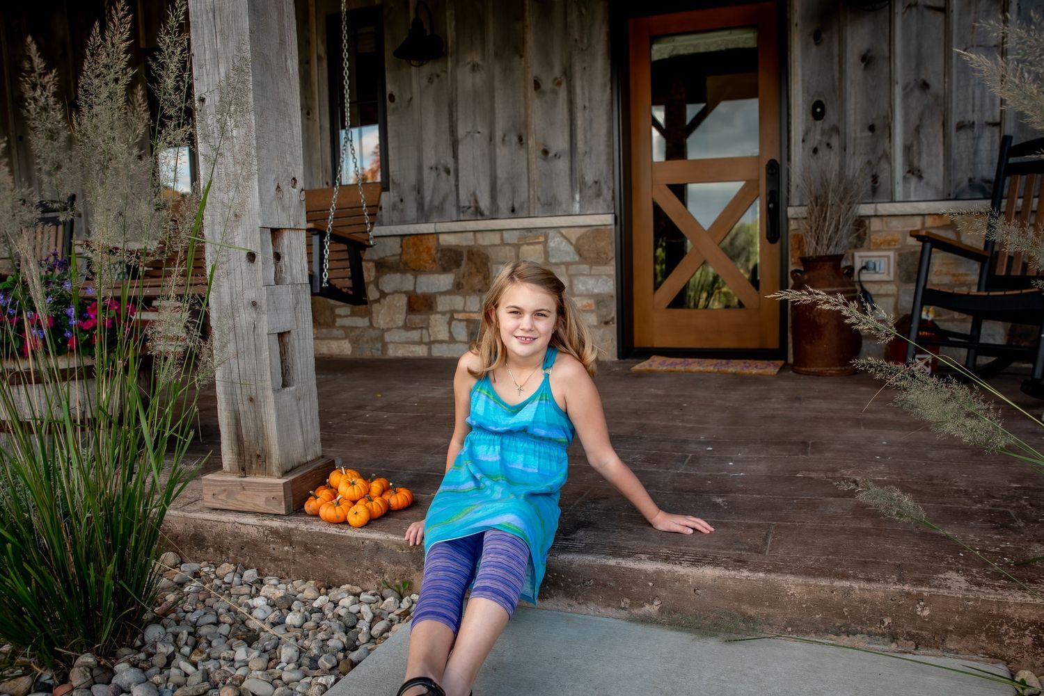 A rustic porch scene with fresh oranges and decorative grasses.