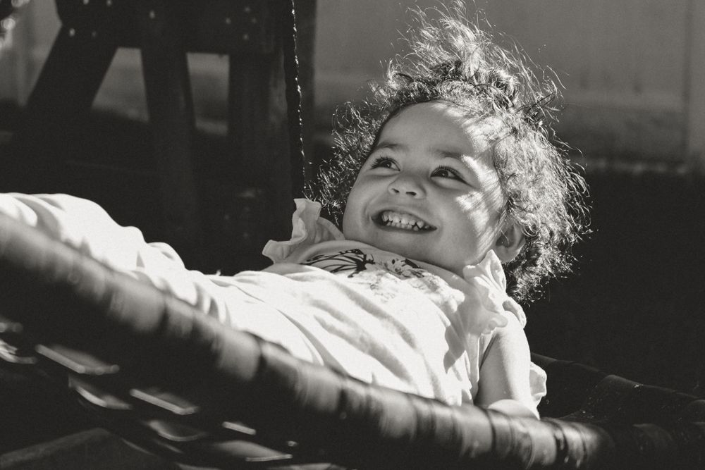 Black and white photo of a joyful child laughing while lying down.