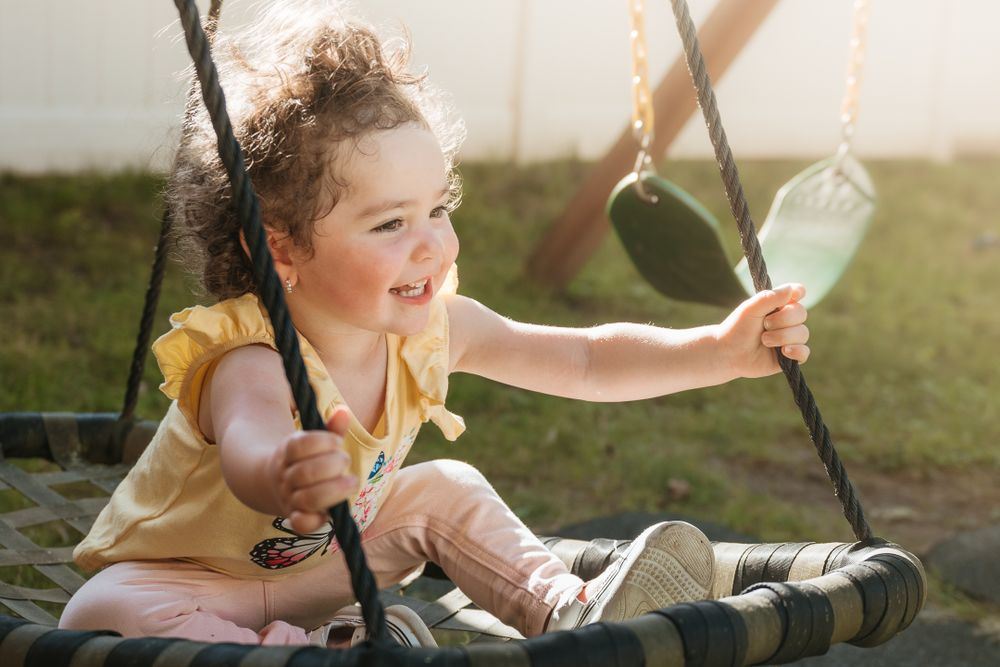 Child swinging and laughing with pure joy in golden afternoon sunlight.