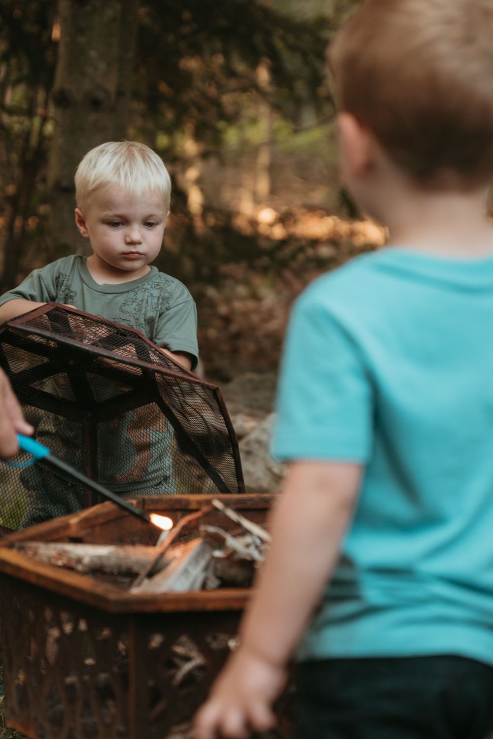 Children exploring outdoor gear and equipment in a forest setting.