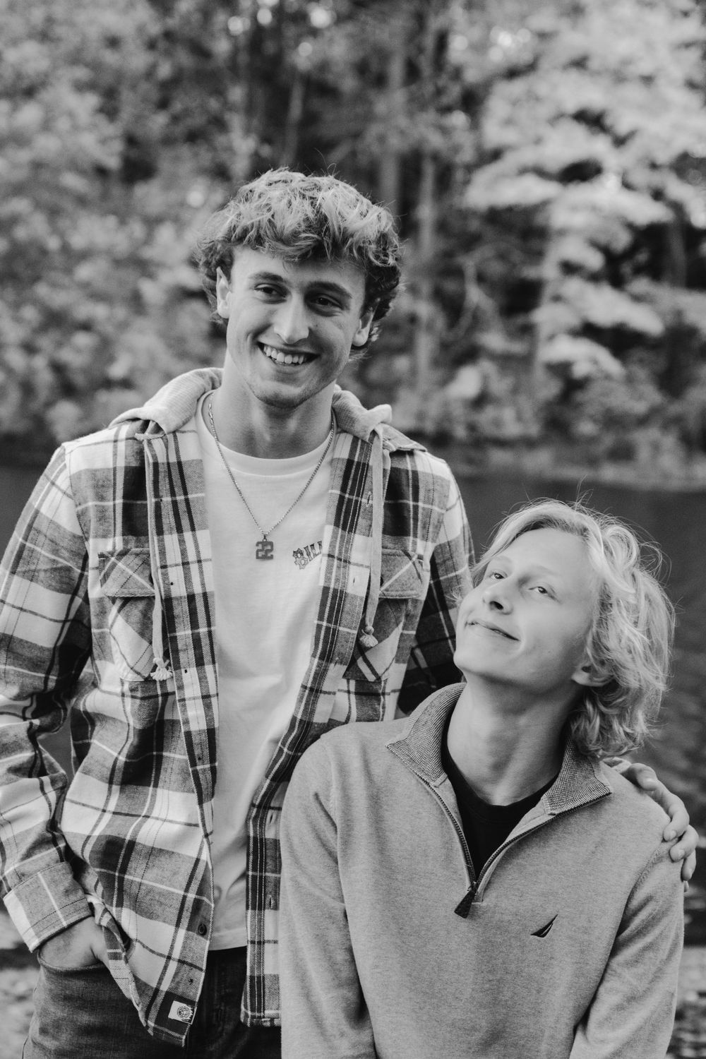 Family members sharing candid laughing moments together in black and white outdoor photo.