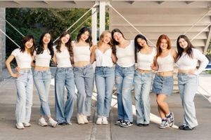 Group of high school dance team dancers in matching white crop tops and blue jeans posing together against a white school staircase.