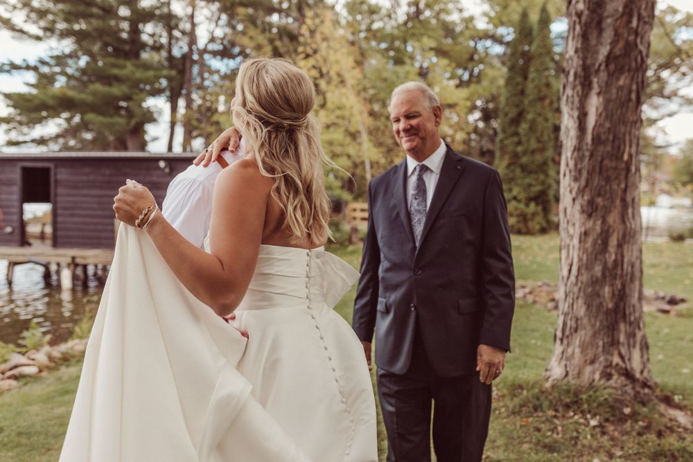 An emotional first look moment between a bride in white and a suited gentleman in an outdoor setting.
