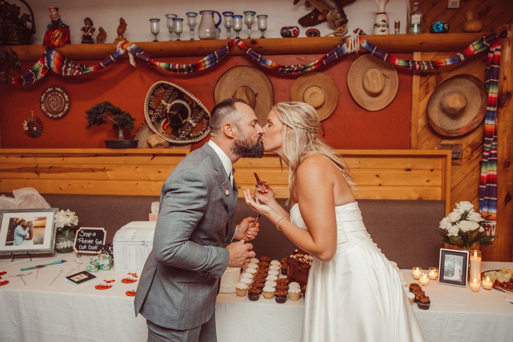 Couple shares intimate moment at rustic western-themed wedding reception with cowboy decor.