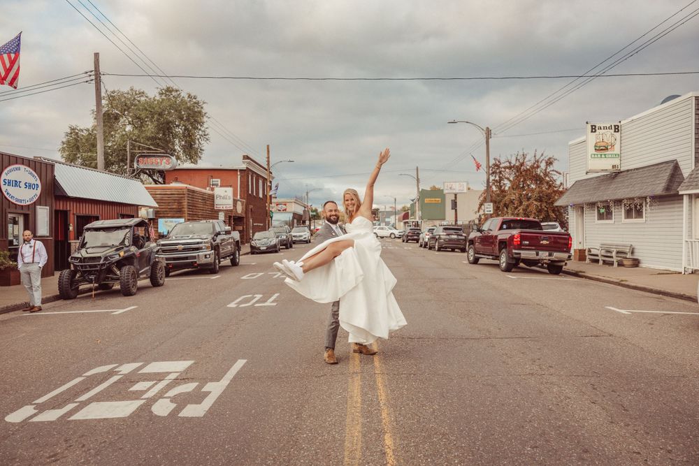 Person in white dress dances joyfully in the middle of a small town street.