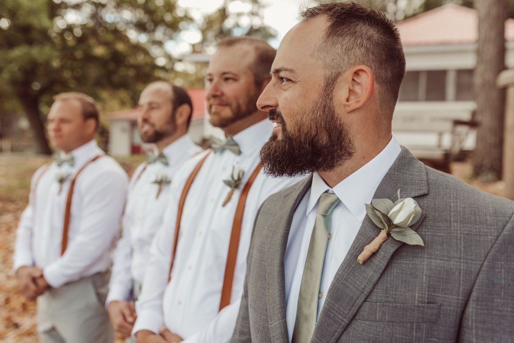 Wedding party members in white shirts and suspenders fishing from a dock.