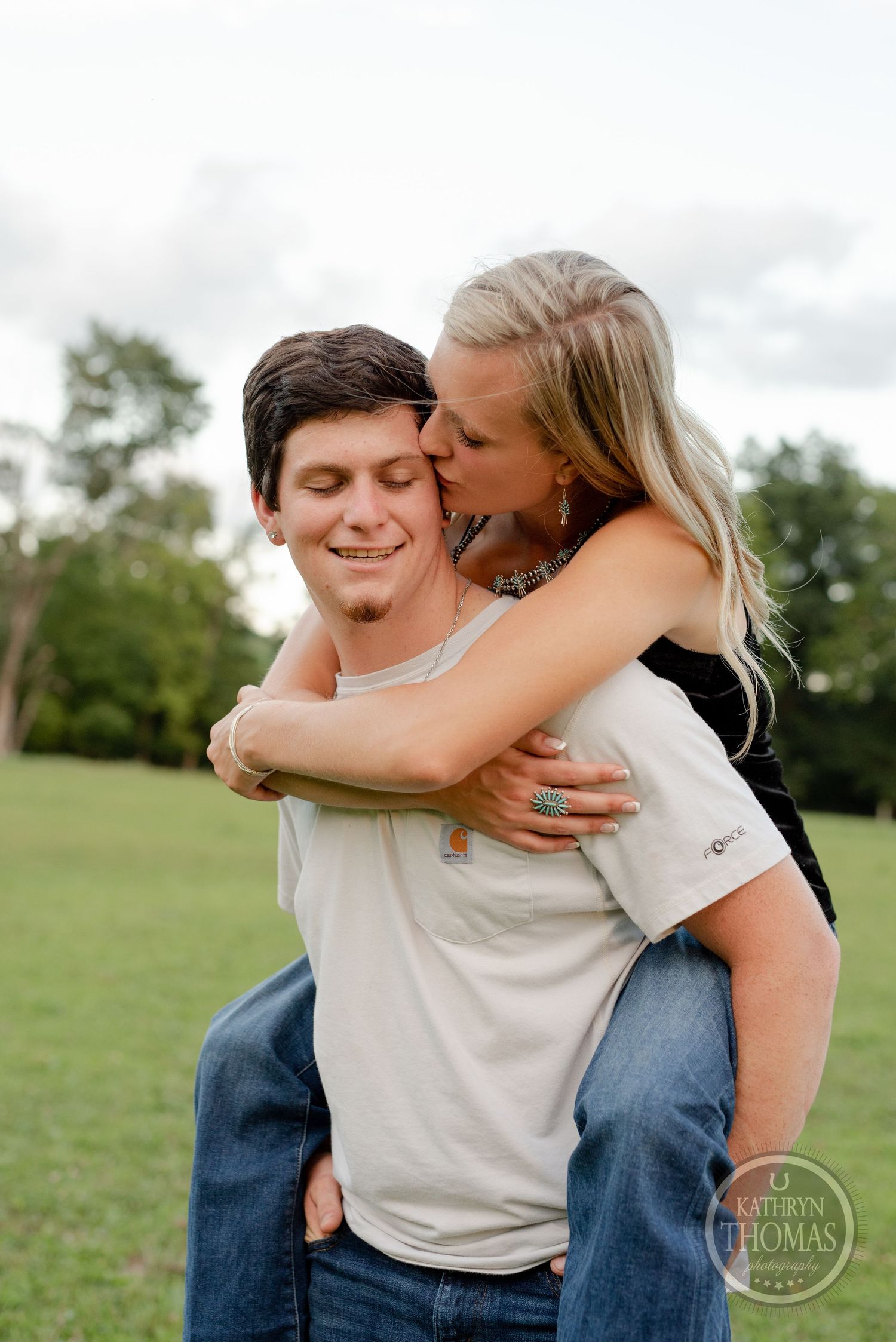 A tender embrace between a couple in a grassy field during a photo session.