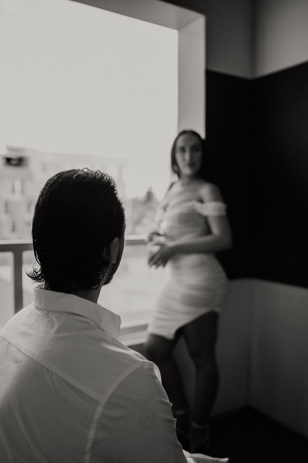 Silhouetted figures in a moody indoor setting with natural light streaming through windows.