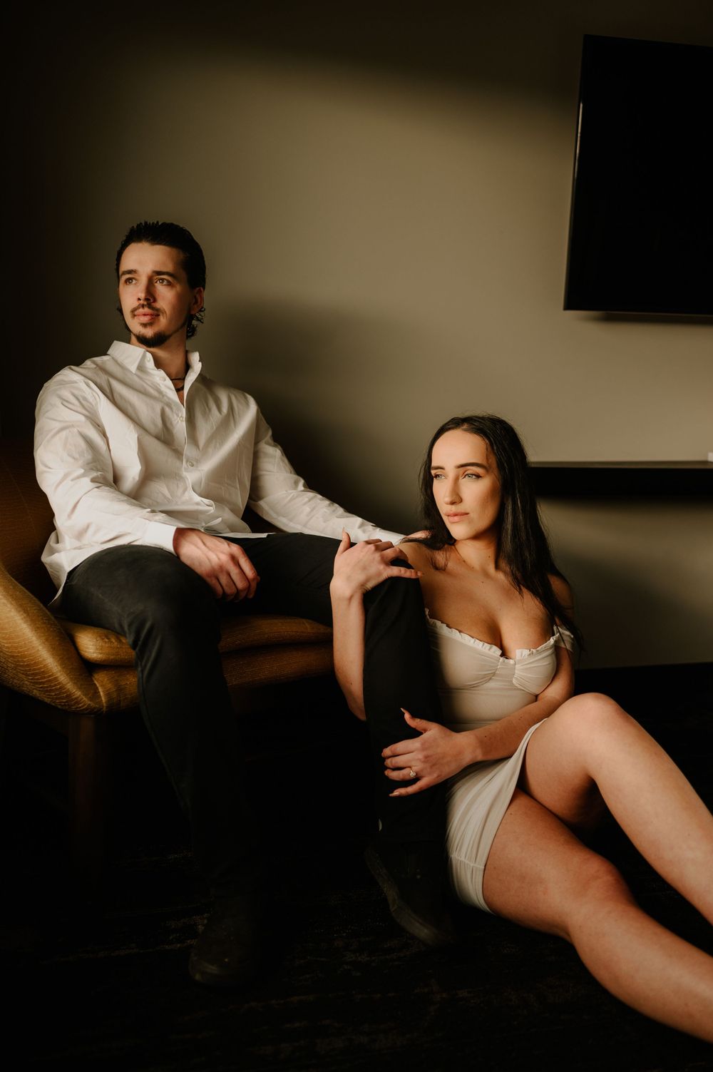 Moody boudoir photography session in a dimly lit room with dramatic shadows.