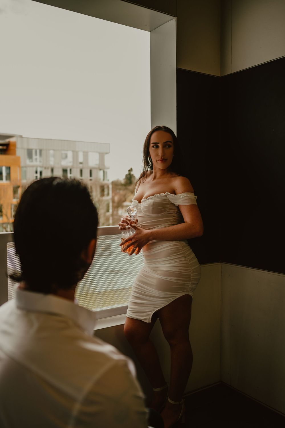 Silhouetted figures by a window in a minimalist room setting.