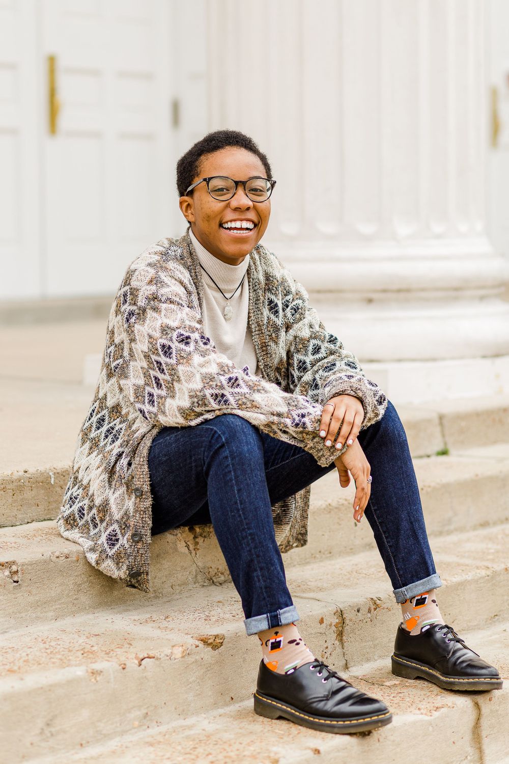 Casual campus portrait on stone steps wearing a snake print cardigan and jeans.