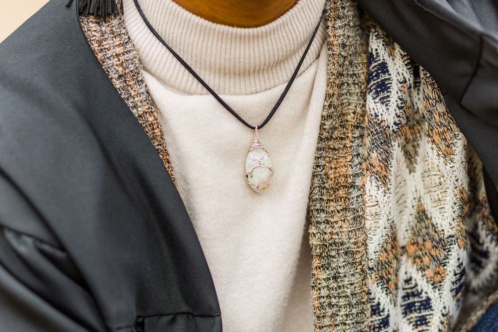Close-up of layered necklaces and white turtleneck with tweed cardigan detail.