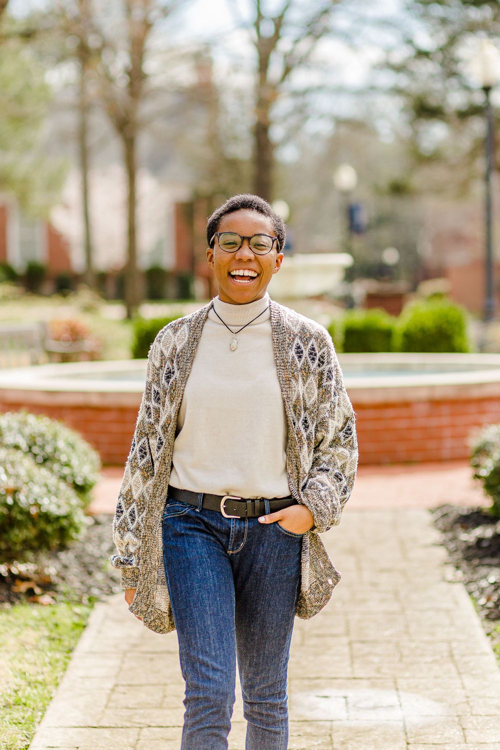 Spring campus portrait with patterned cardigan and casual denim on brick walkway.