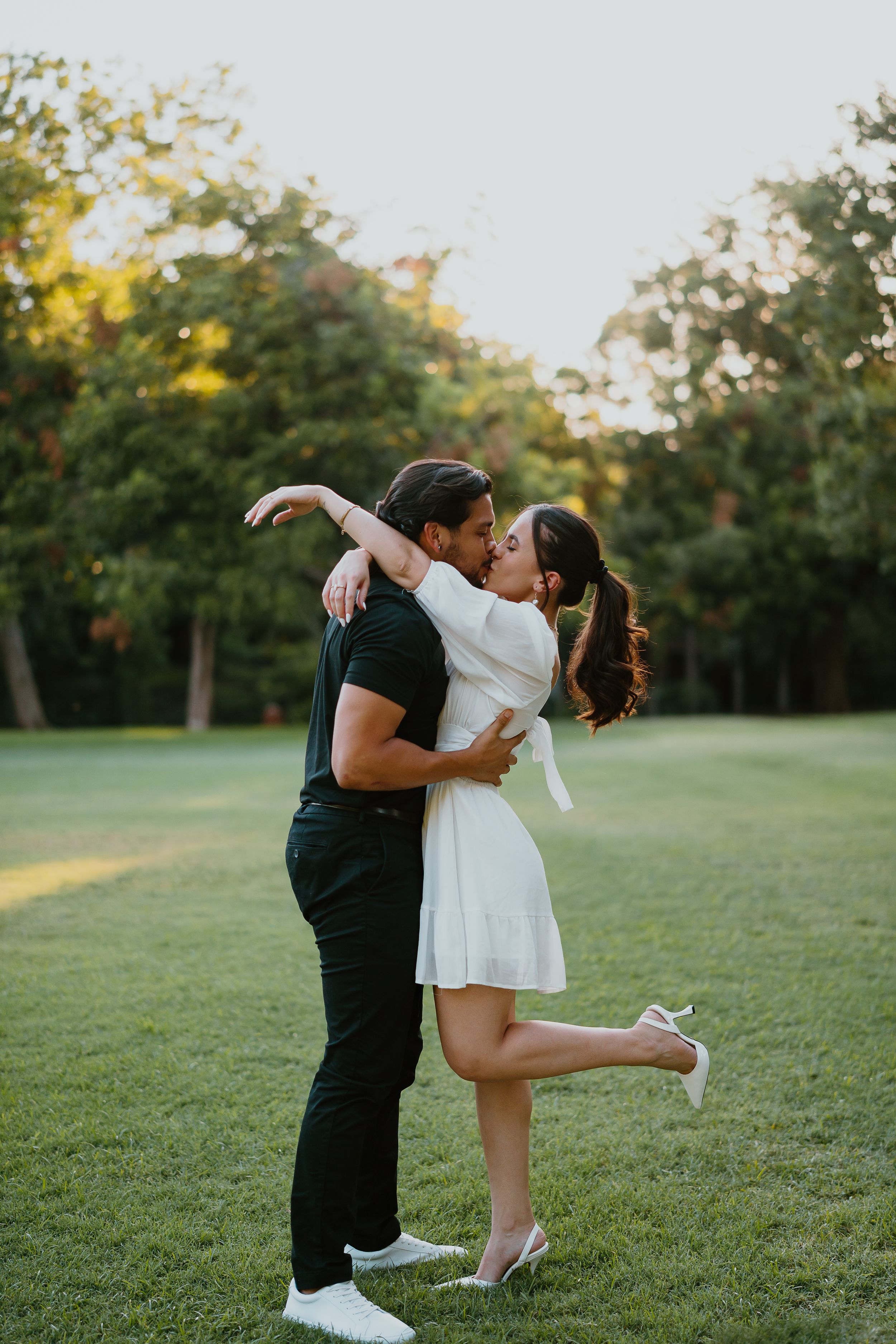 couple kissing during engagement photos outside in highland park texas. alex marie photography.