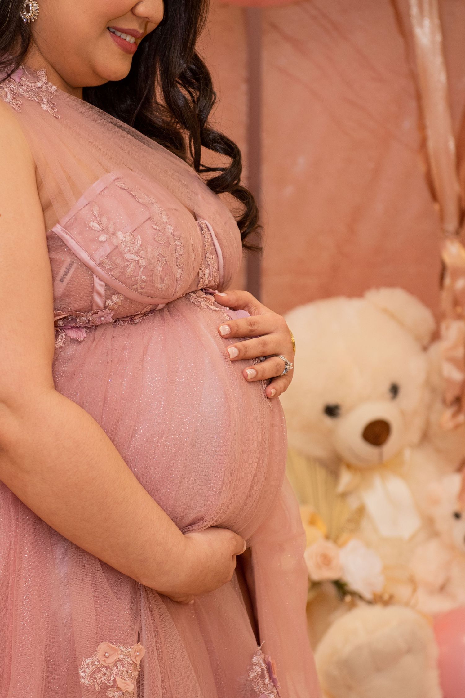 Close-up shot of a pink tulle maternity gown with lace details and a baby bump.