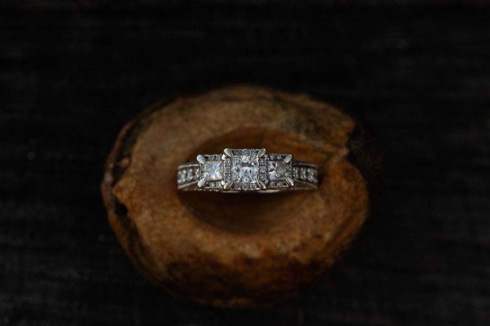 A sparkling diamond engagement ring displayed on a rustic wooden surface.