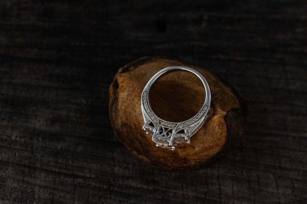 An elegant diamond engagement ring photographed on dark wood.
