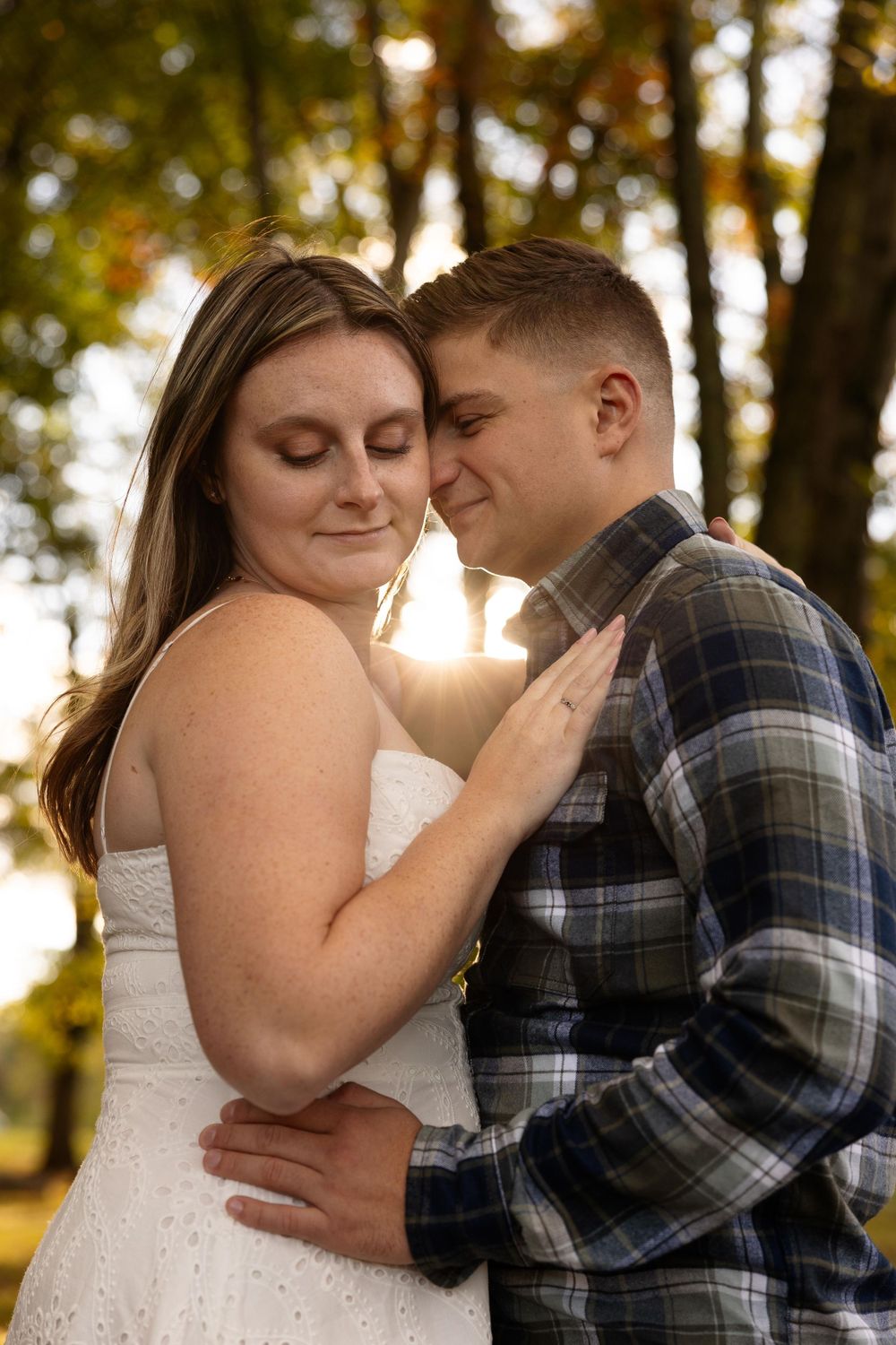 A tender embrace captured in warm sunlight filtering through autumn trees.