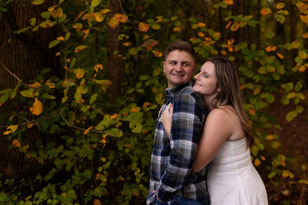 Intimate moment captured between couple against colorful fall leaves background.
