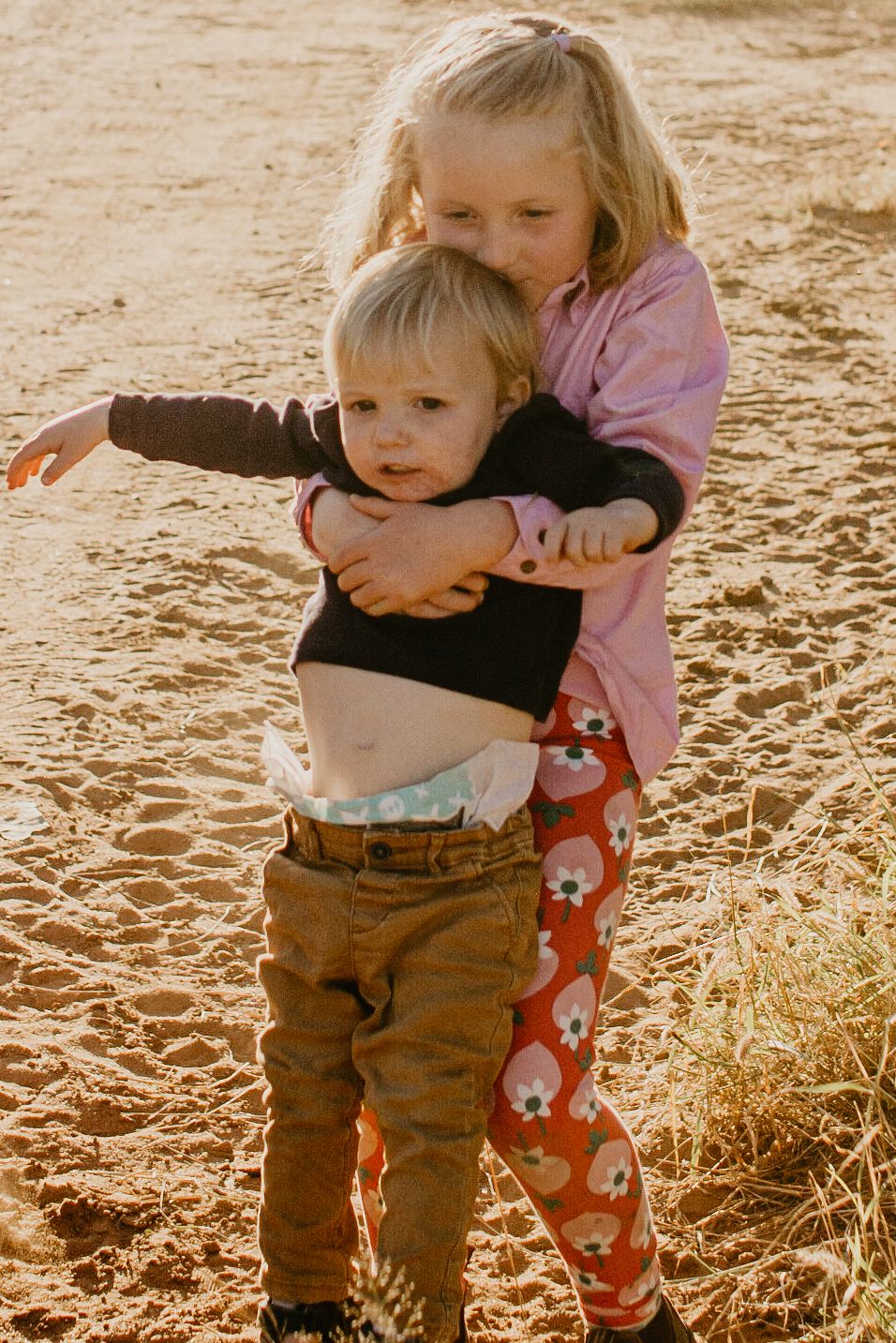 Sister carrying younger brother in the paddock