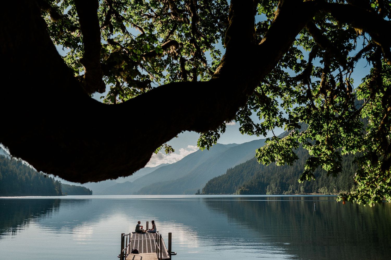 couple sitting on dock at Lake Crescent. Photo by Washington elopement photographer