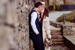 Romantic moment against stone wall with rustic bouquet and autumn scenery.