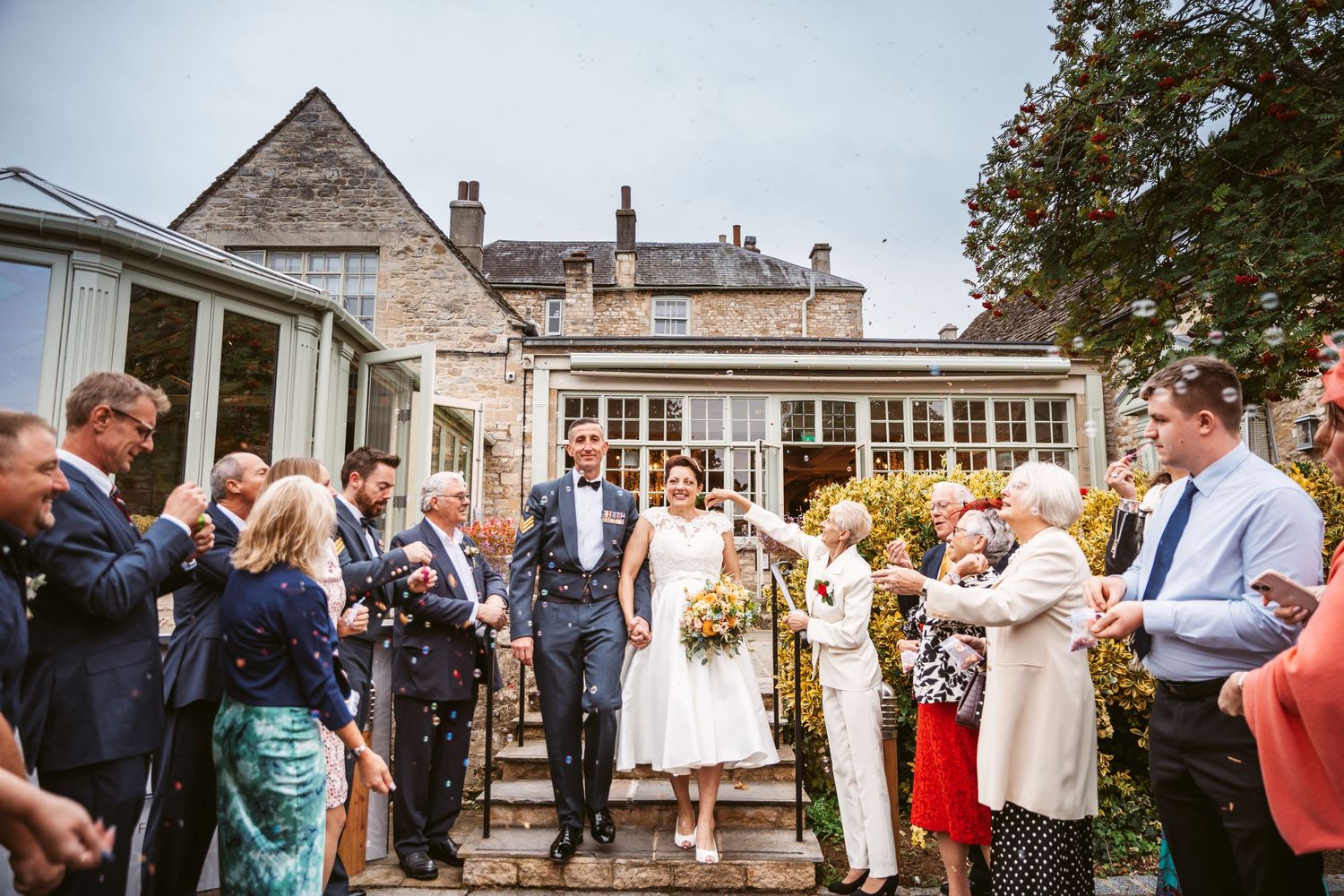 Wedding guests gather outside a beautiful stone building for post-ceremony celebrations.