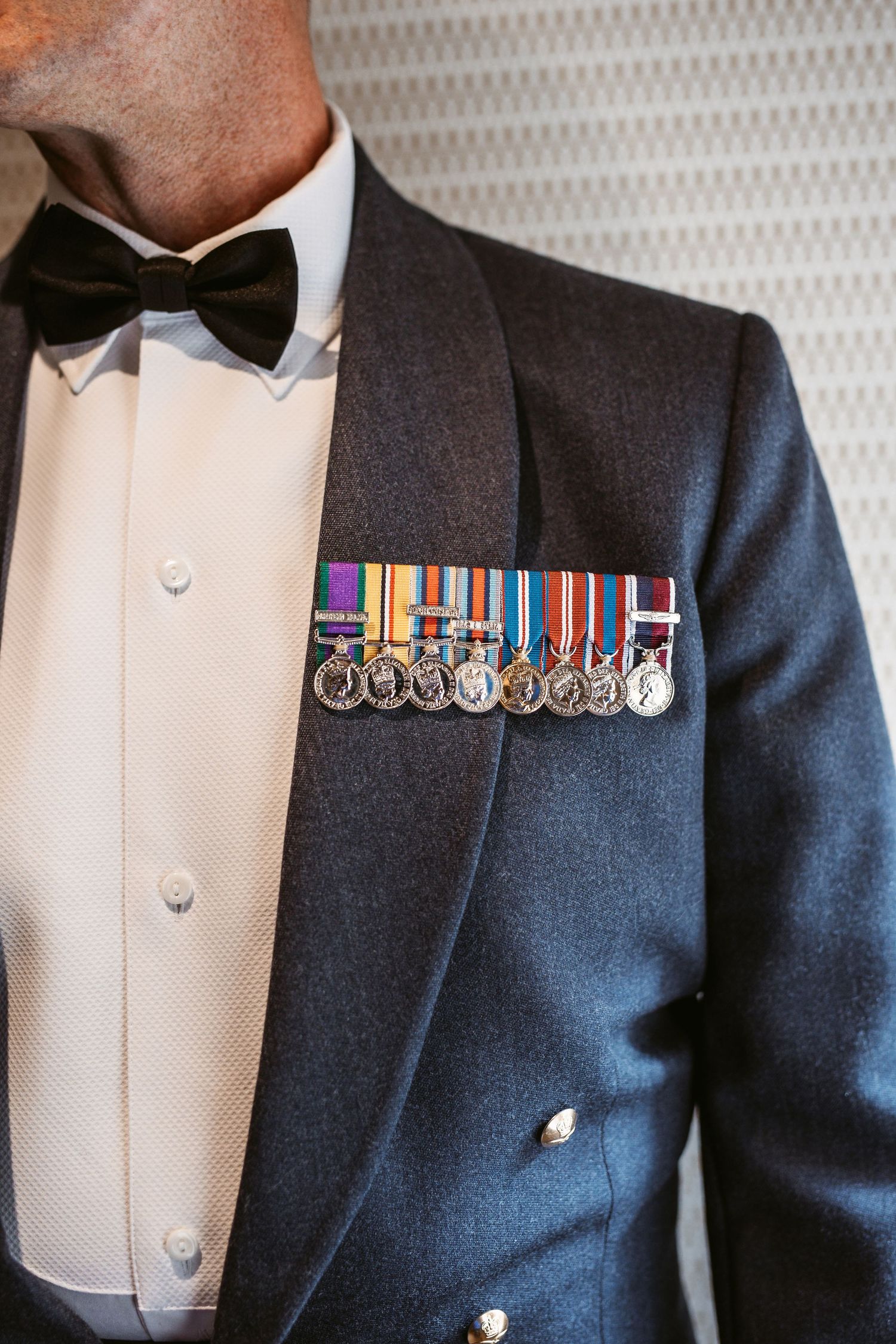 Military dress uniform with decorative medals and bow tie against formal attire.