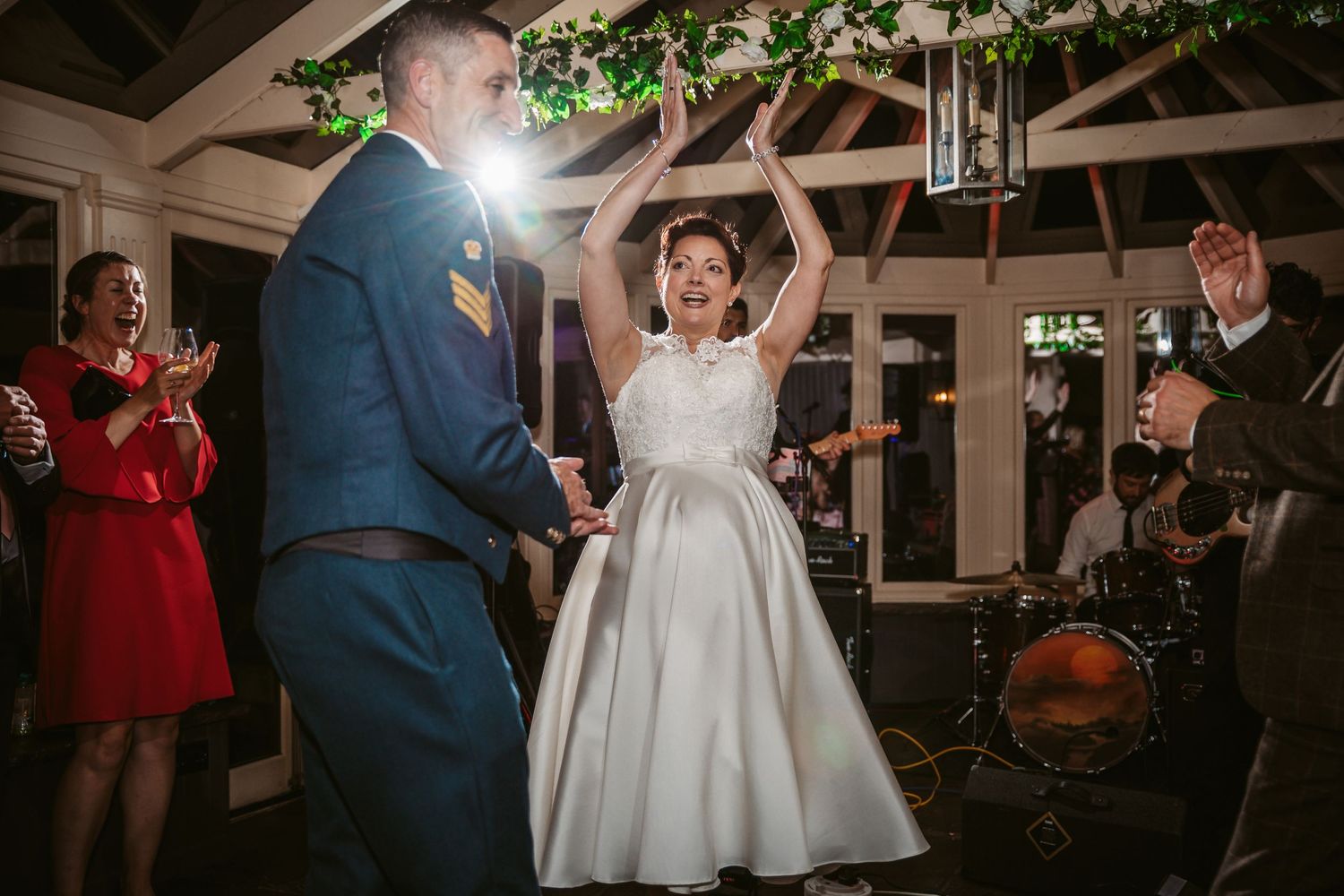Energetic dance moment captured between newlyweds under twinkling lights and greenery.