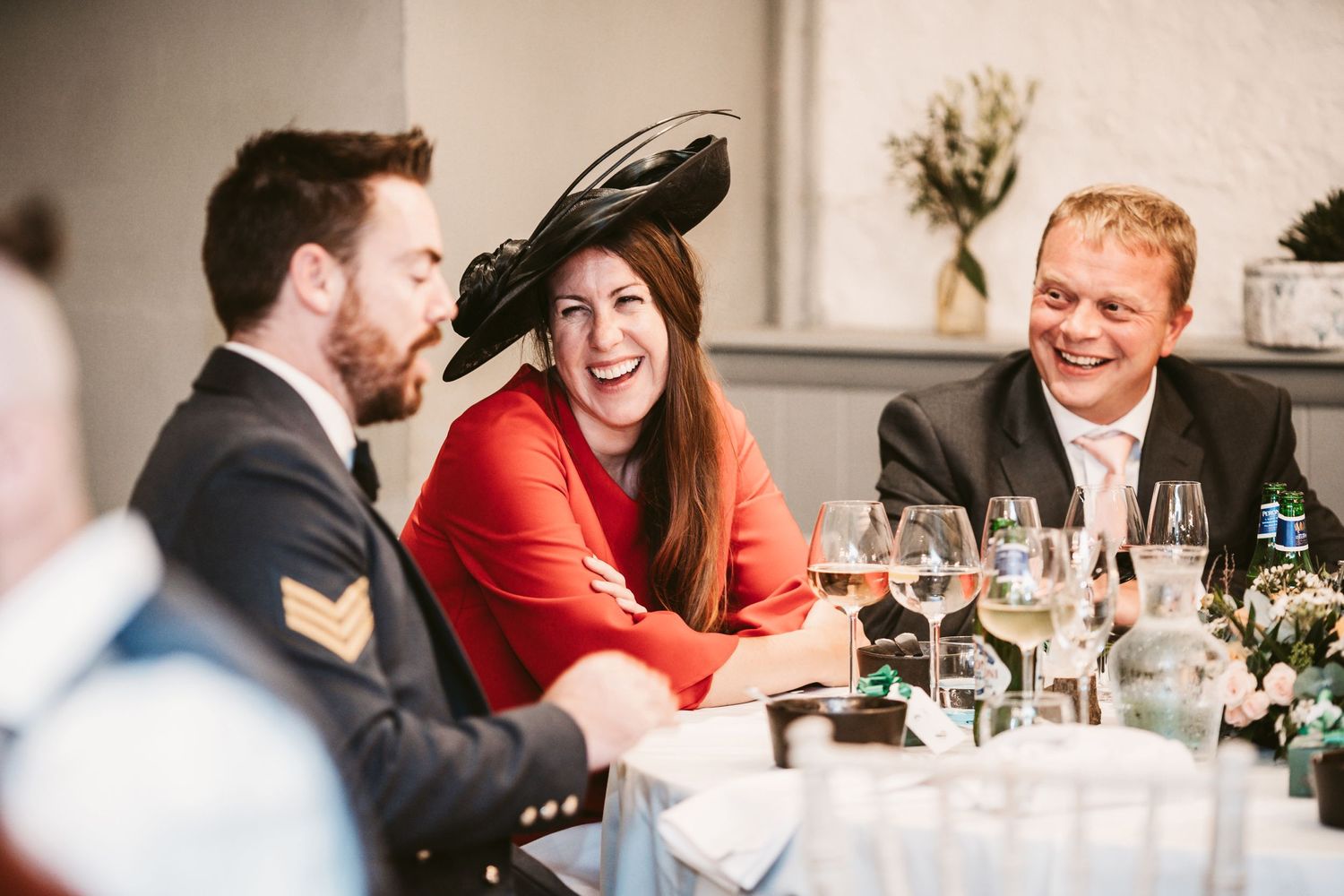 Wedding reception guests enjoying conversation and laughter at dinner table.