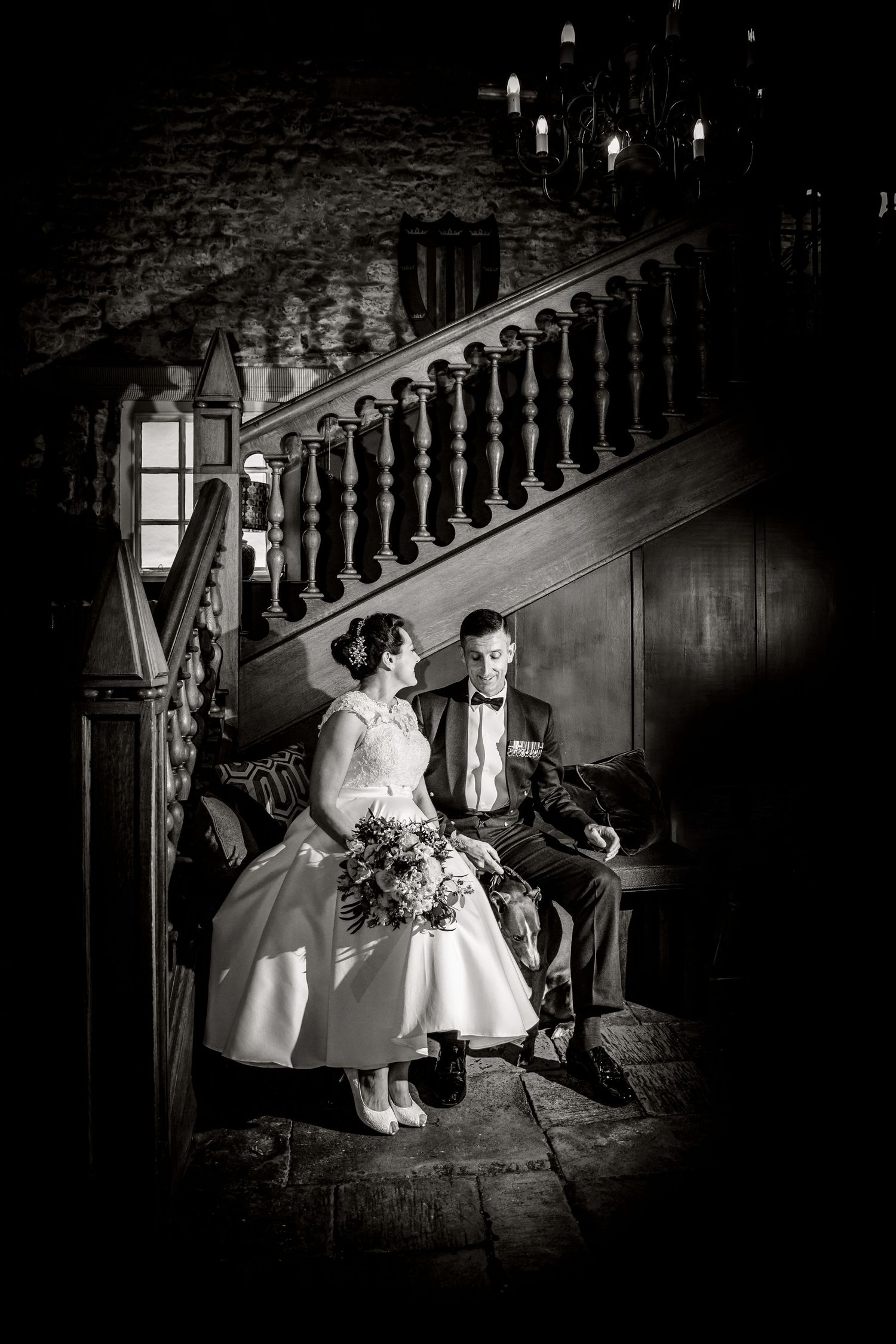Black and white wedding portrait on vintage stairs with dramatic lighting and shadows.