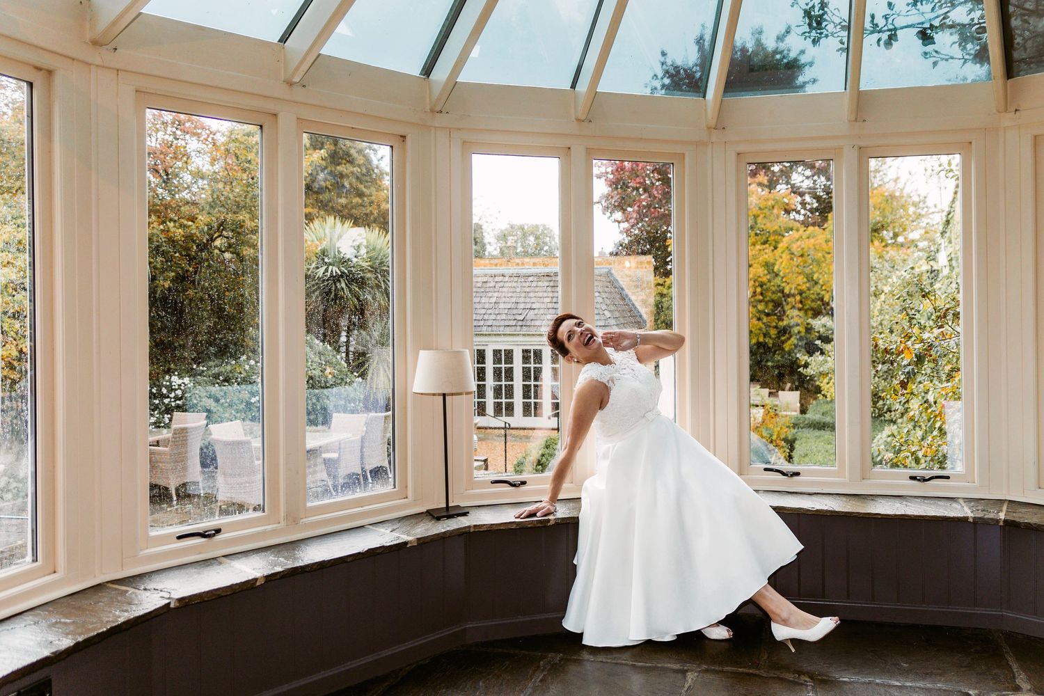 A tea-length wedding dress twirls in an elegant conservatory filled with natural light.